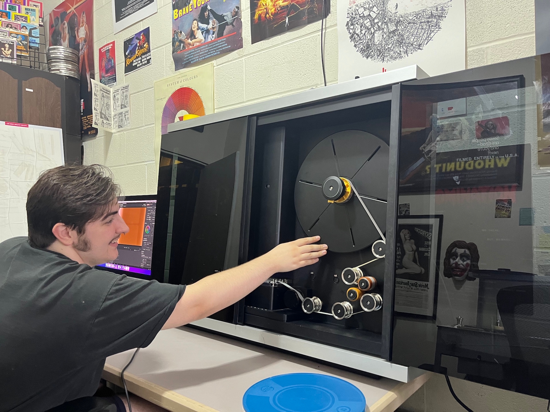 person seated and reaching into a film scanner