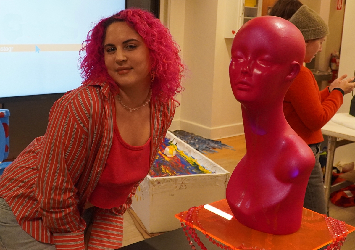 Pink haired student poses next to a pink bust