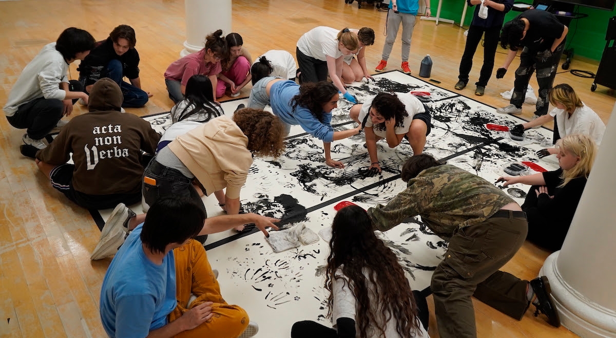Students gathered around a collaborative paint artwork