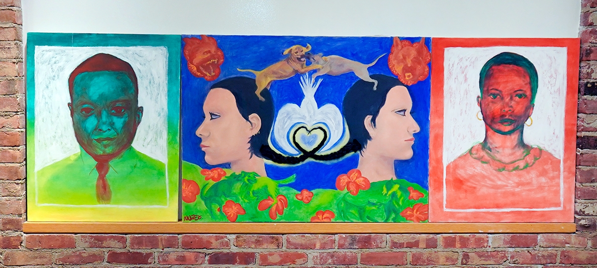three colorful portraits on a brick wall