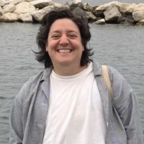 Noah Schamus stands at a waterfront with rocks in the background