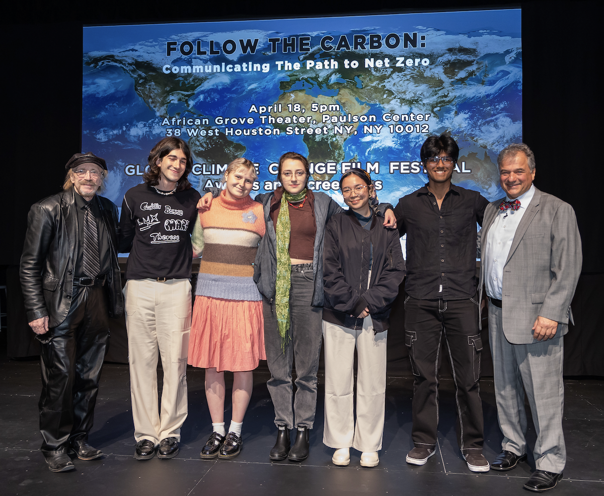 Winners of the 2023 Global Climate Change Film Festival standing on stage in front of a screen with a photo depicting the earth as seen from space behind them.