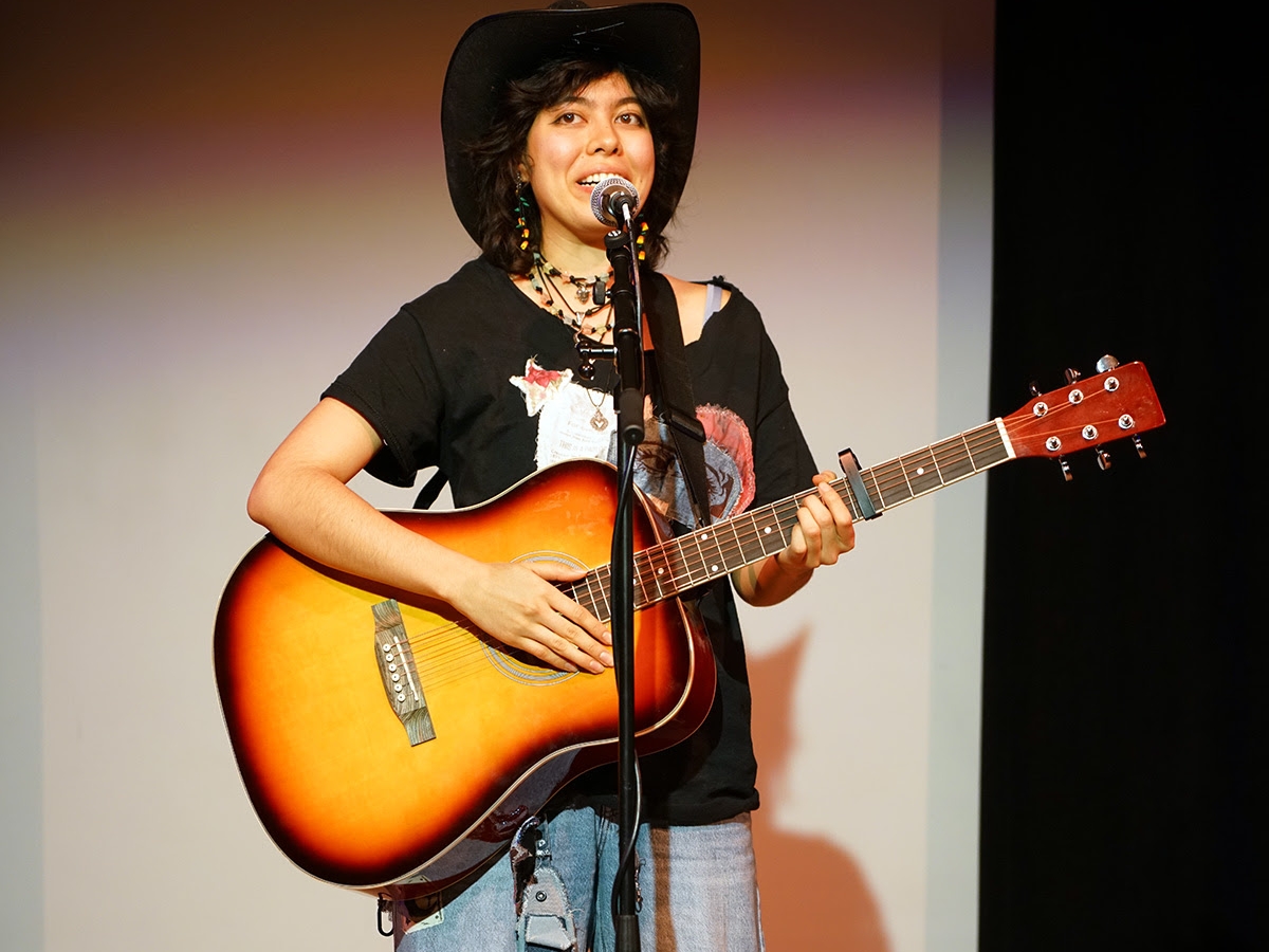 Student singing and playing a guitar