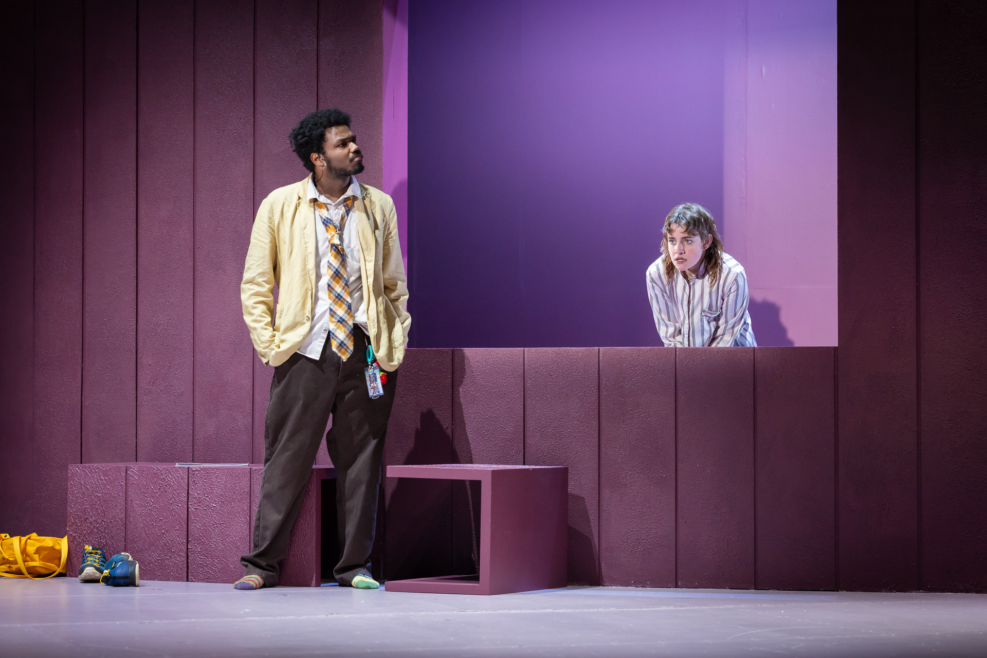 two people standing on a stage, one looking through a window