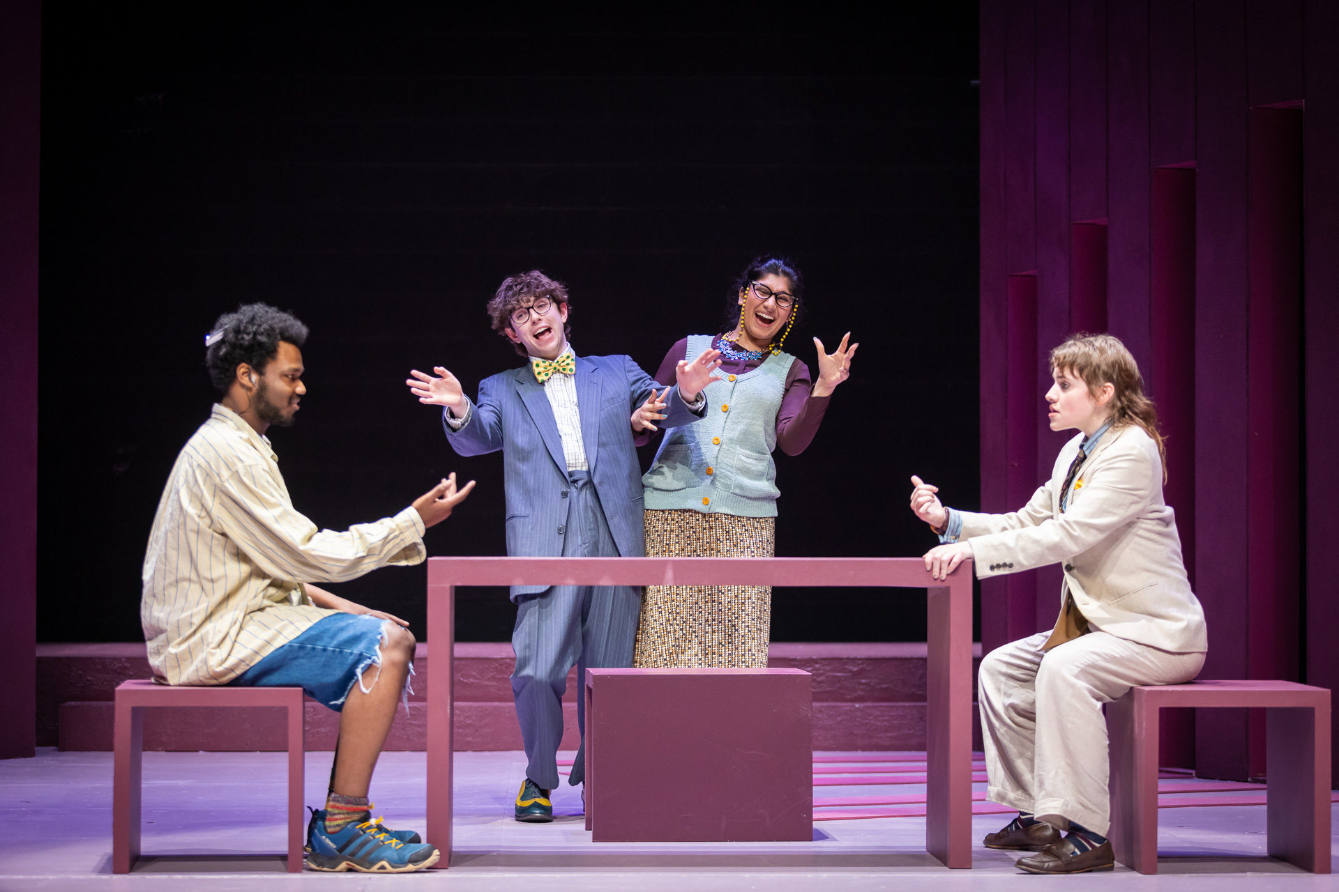 two people sitting at a table, with two people standing behind the table cheering