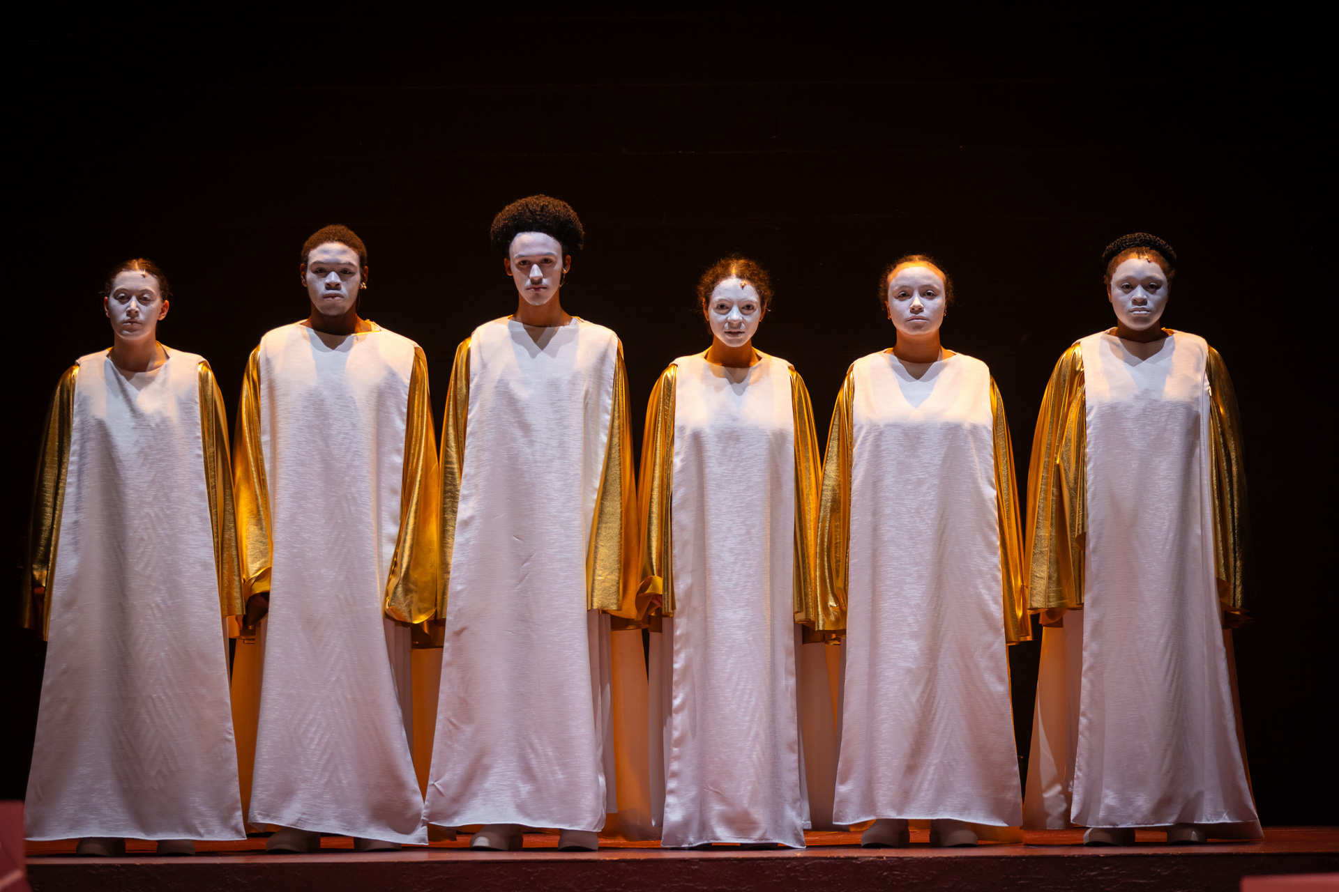 people lined up next to each other in white and gold robes