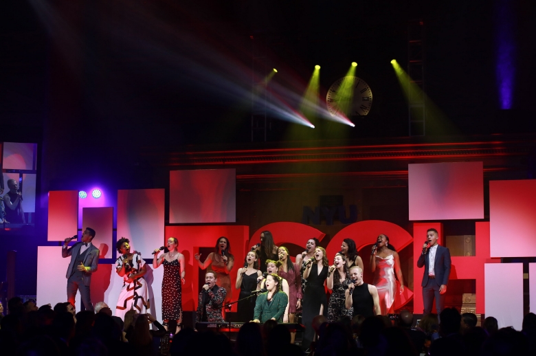 Shaina Taub and student performers on stage in front of a large red 