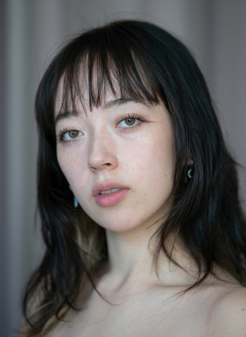 student with dark brown shoulder length hair and bangs. 