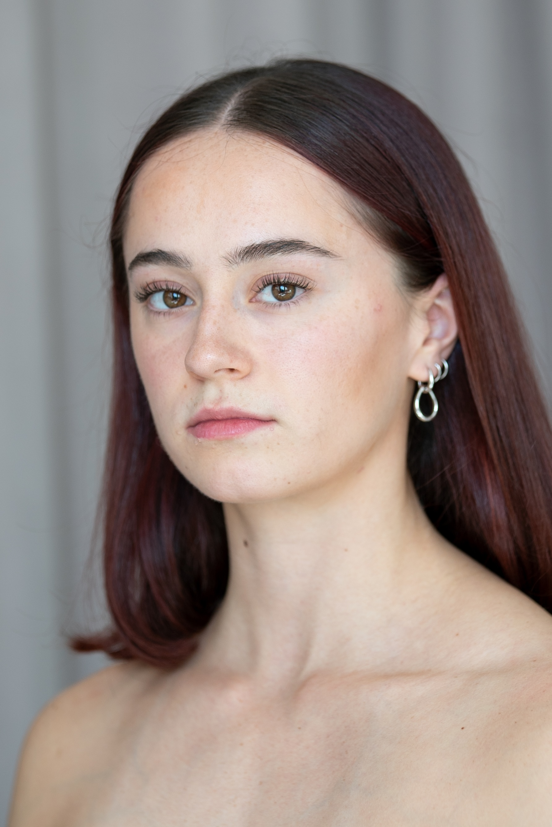 student with brown eyes and brown hair in a center part. 