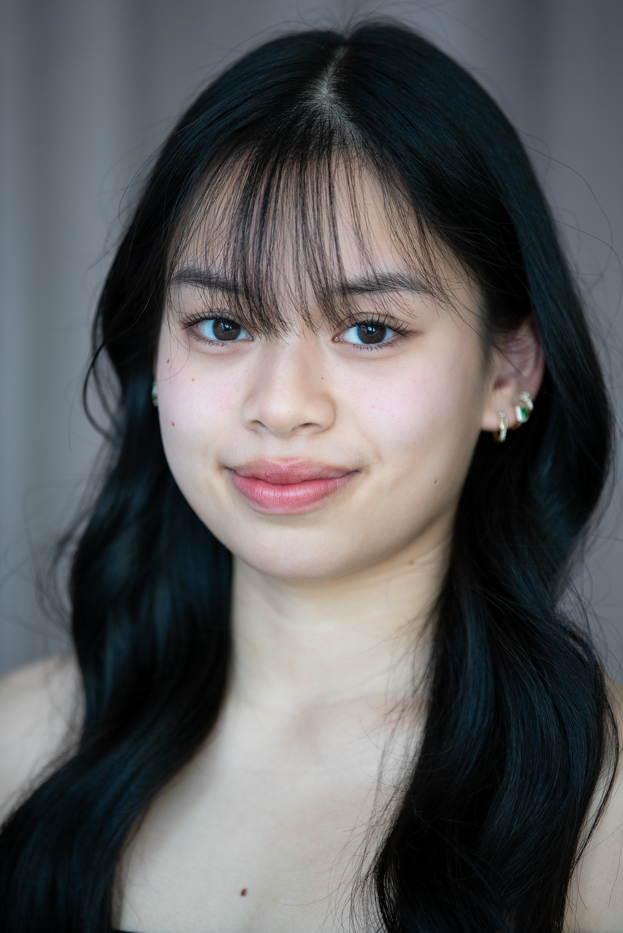 student with dark eyes and dark hair with wispy bangs. 