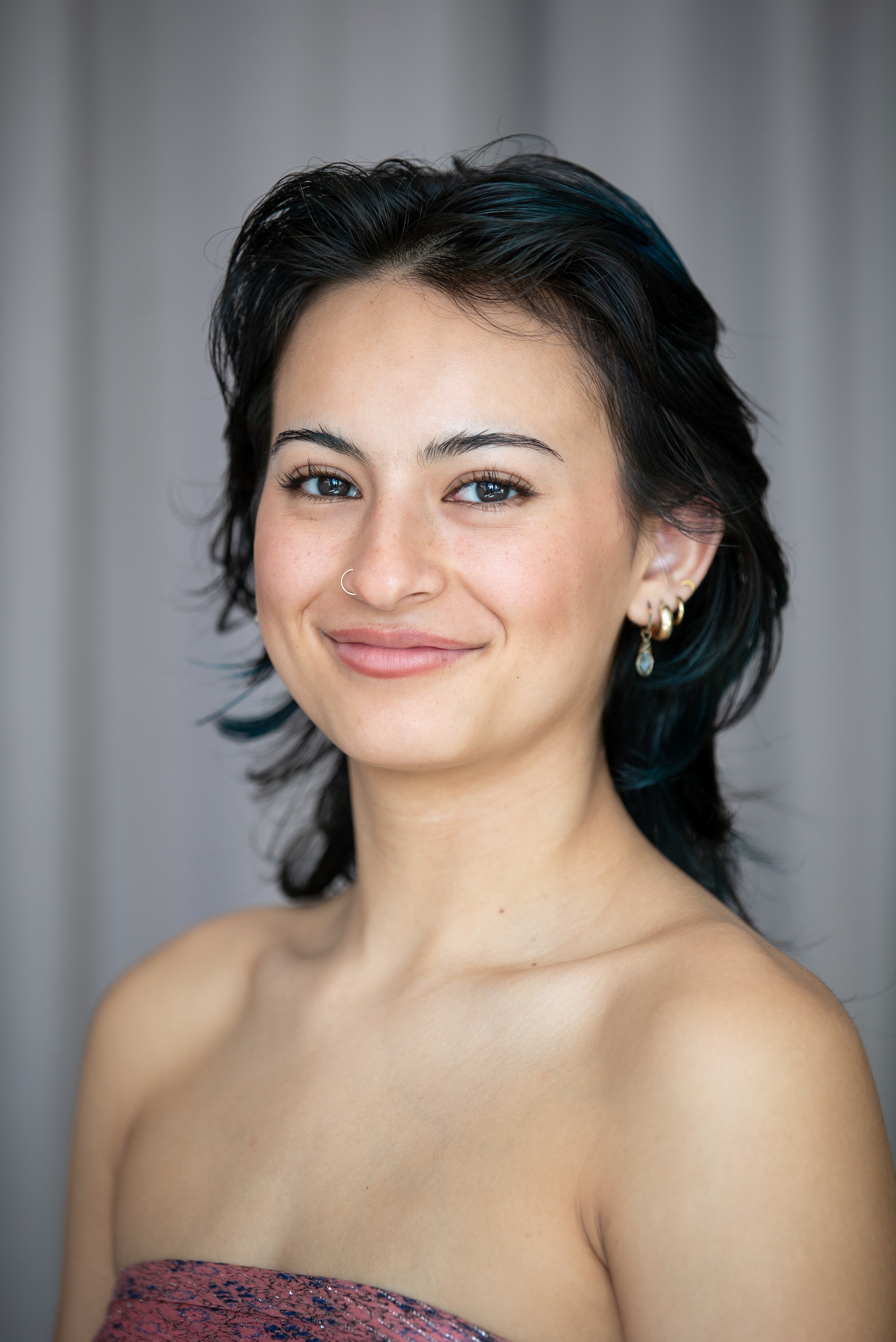 student with brown hairs and shoulder length brown hair cut in layers smiles at the camera. 