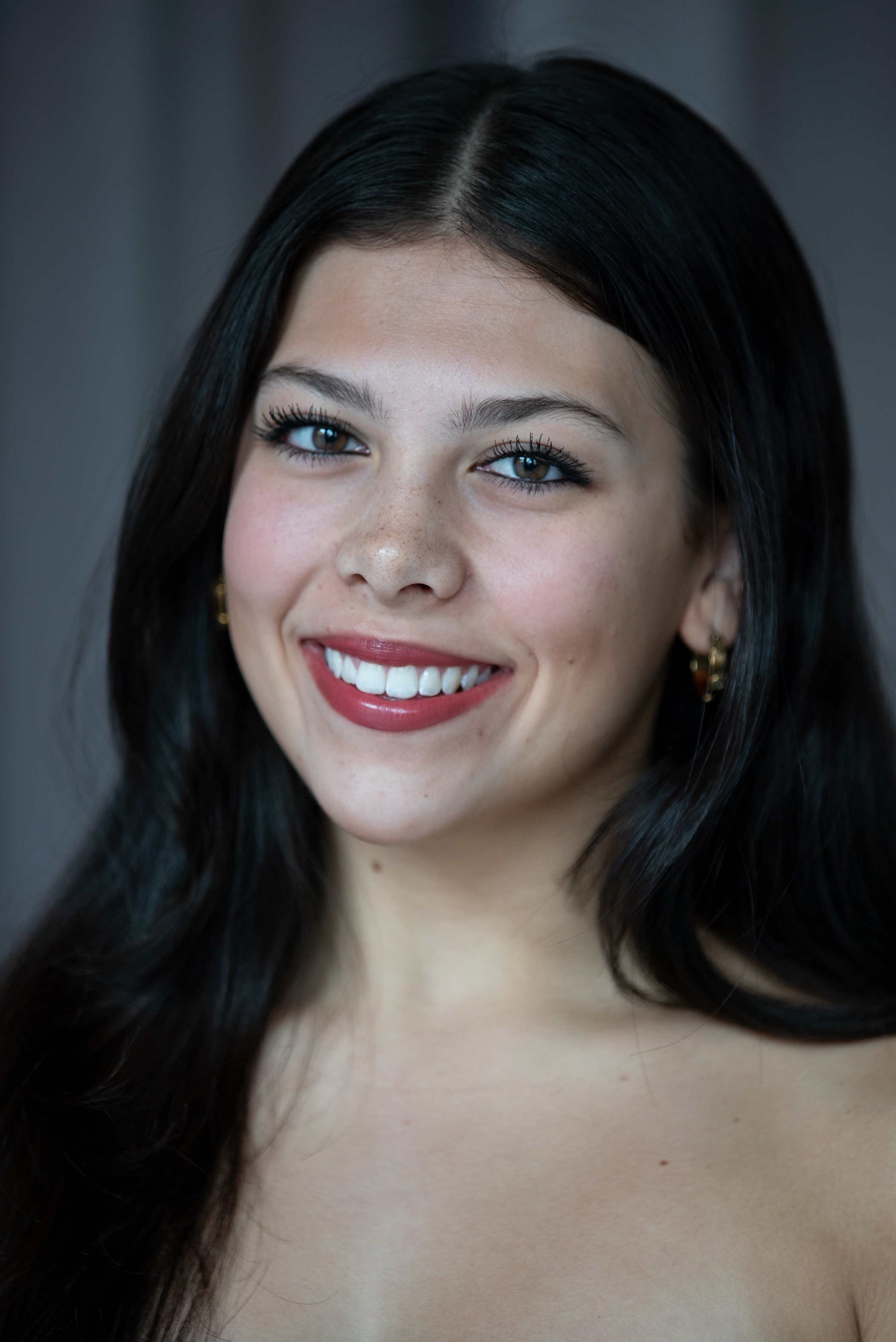 smiling student with red lipstick and dark hair in a center part