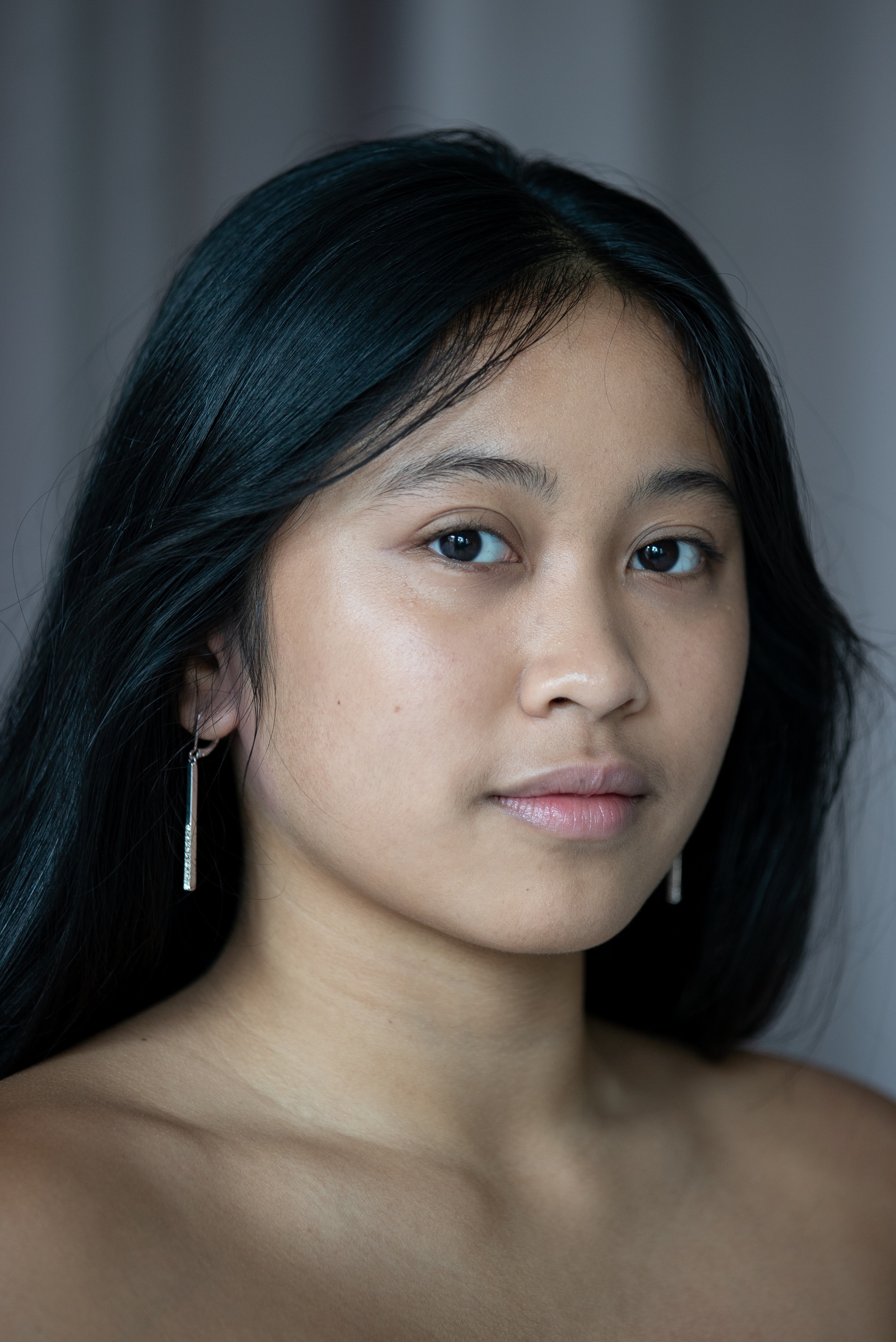 student with long silver earrings and dark brown hair past the shoulders. 