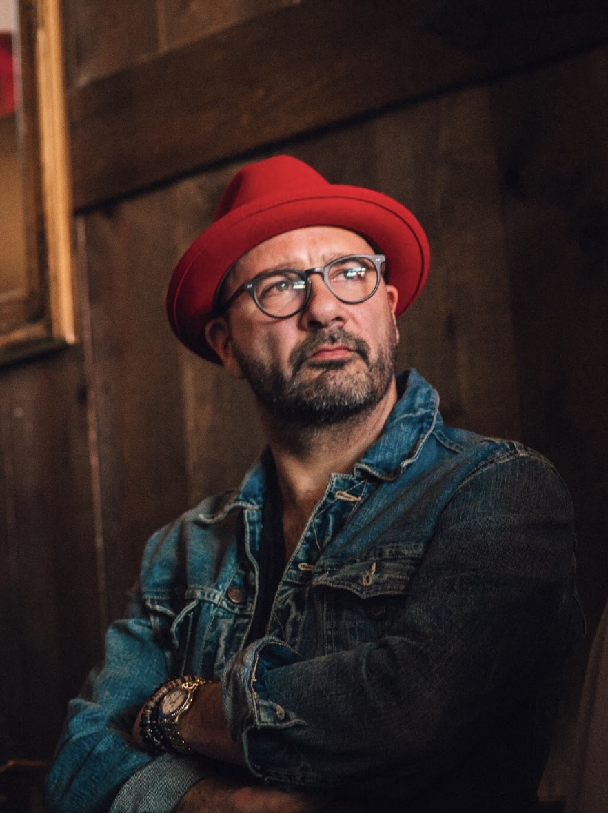 Headshot of faculty member Jeff Peretz with thick black glasses and red hat