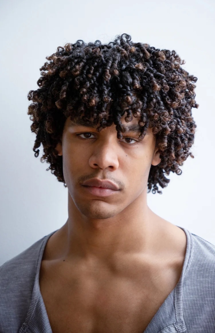 man with curly hair in grey shirt. 