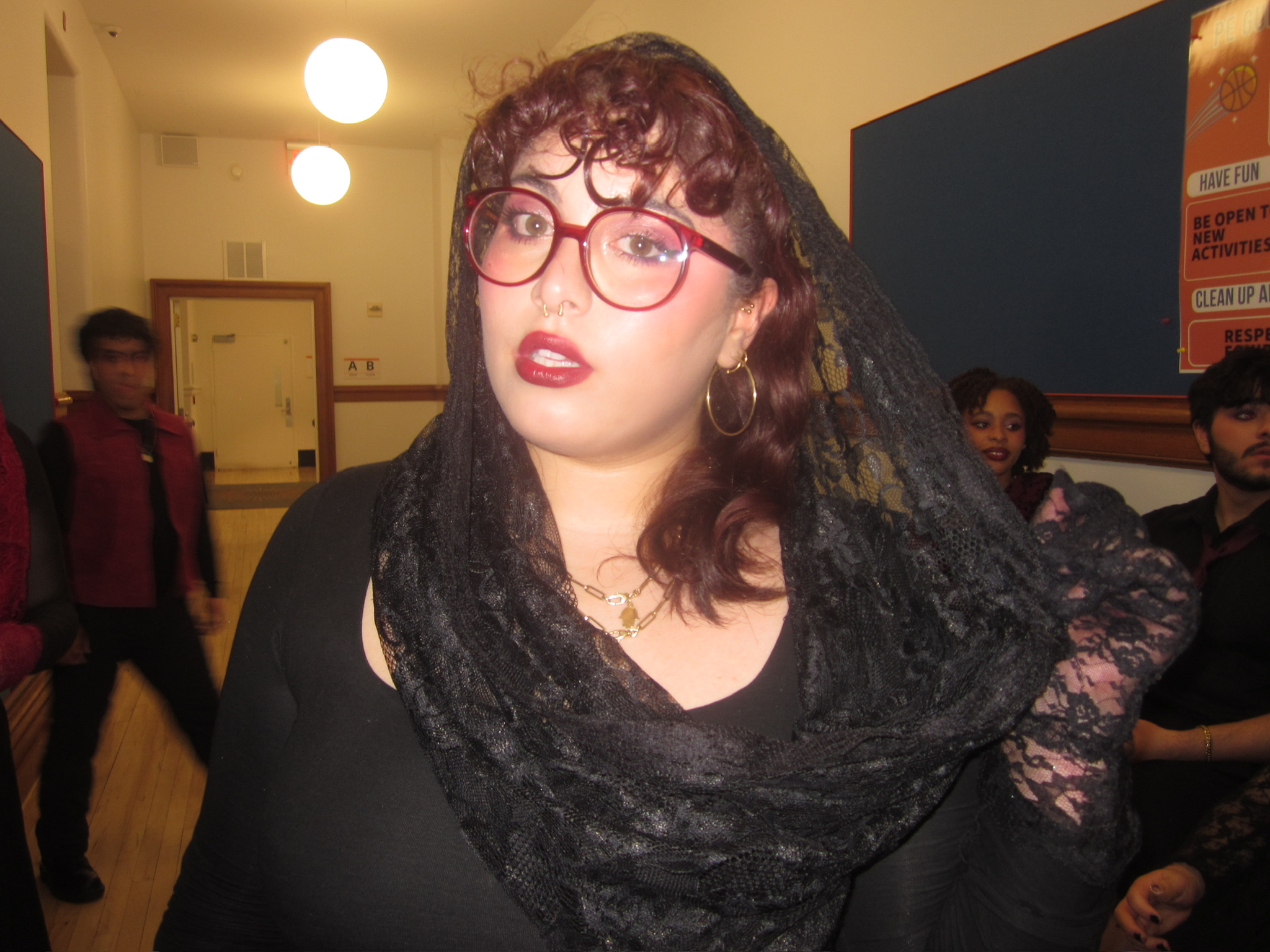 Student with black dress and scarf with red glasses and curly auburn hair