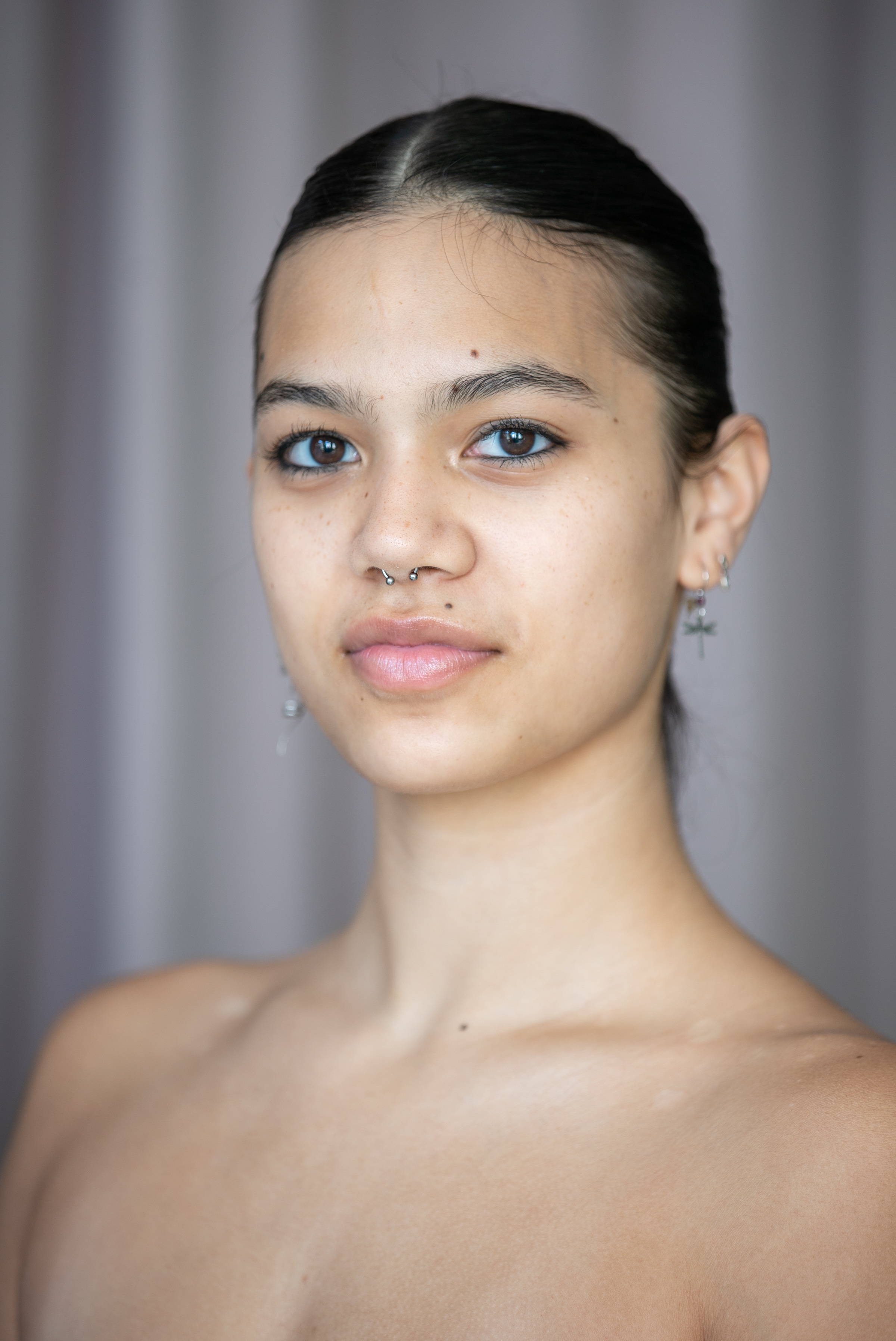 student with dark hair and dark eyes against a neutral background. 