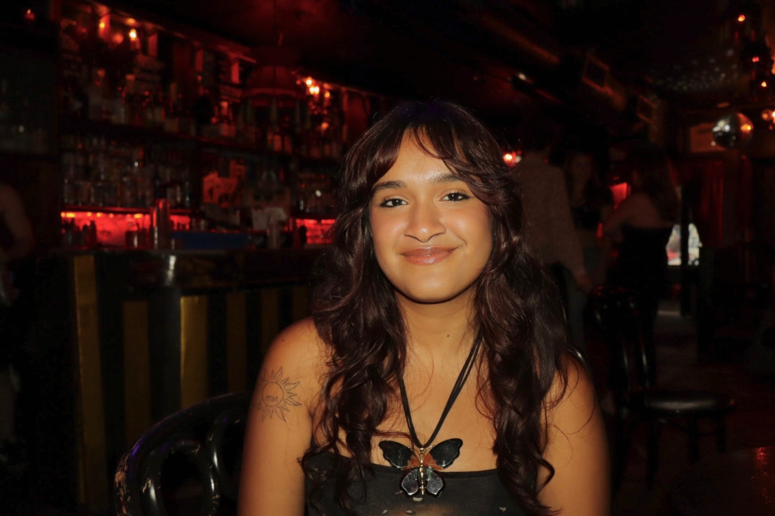 Grinning student with black top, pleasant grin, and long dark hair
