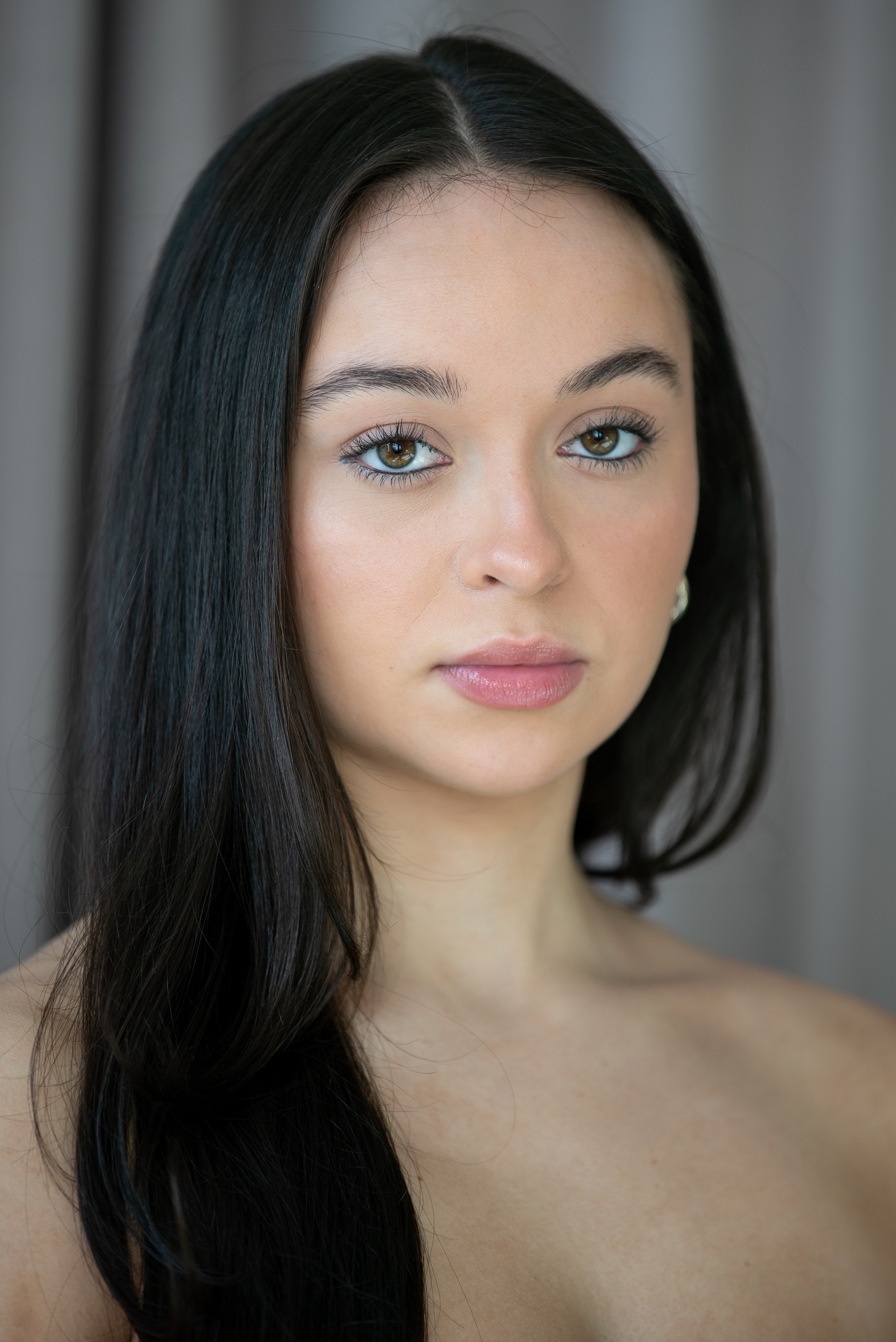 student with brown eyes and long dark brown hair against a neutral background