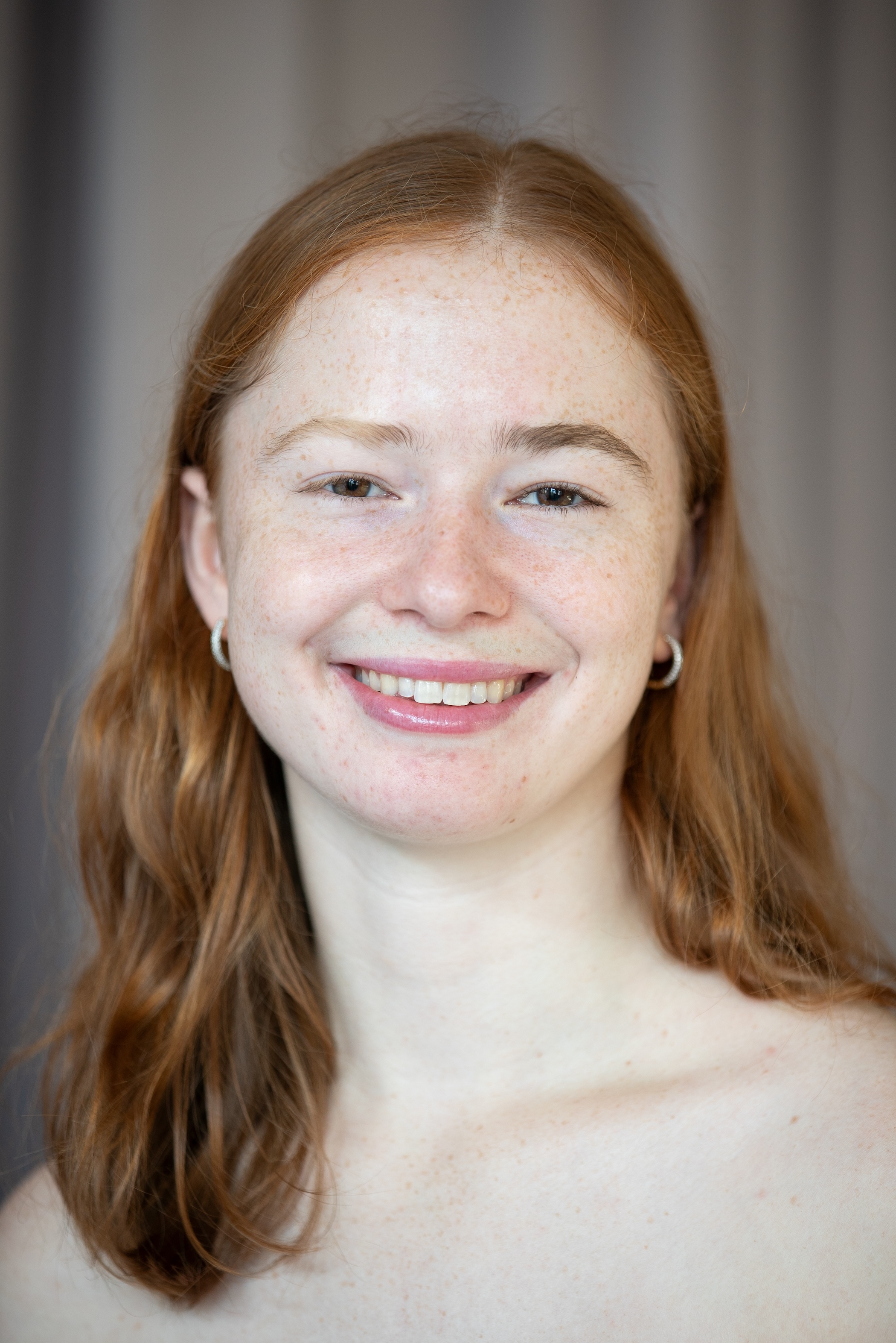 smiling student with red hair past her shoulders in a center part. 