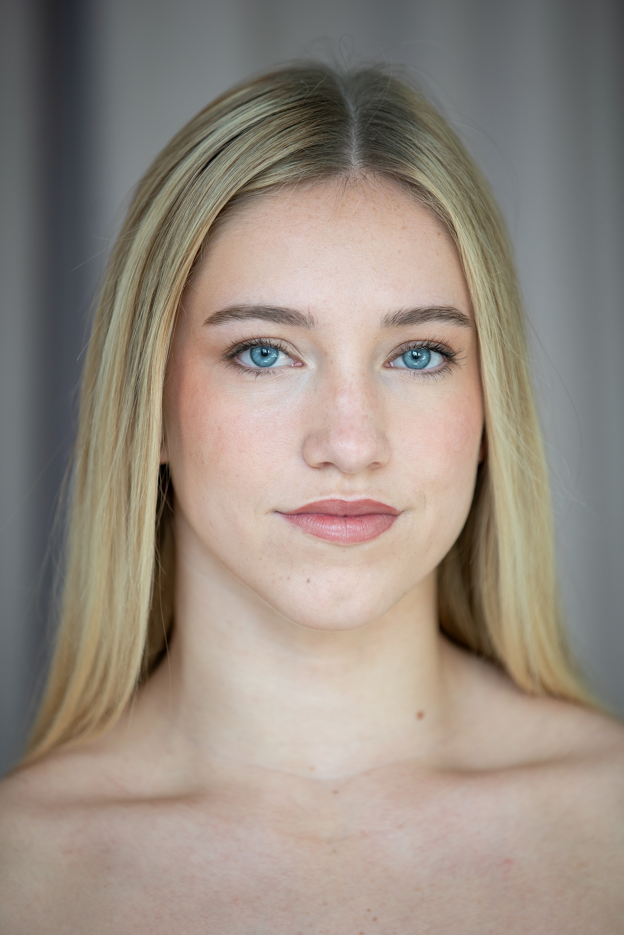 student with blue eyes and blonde hair in a center part