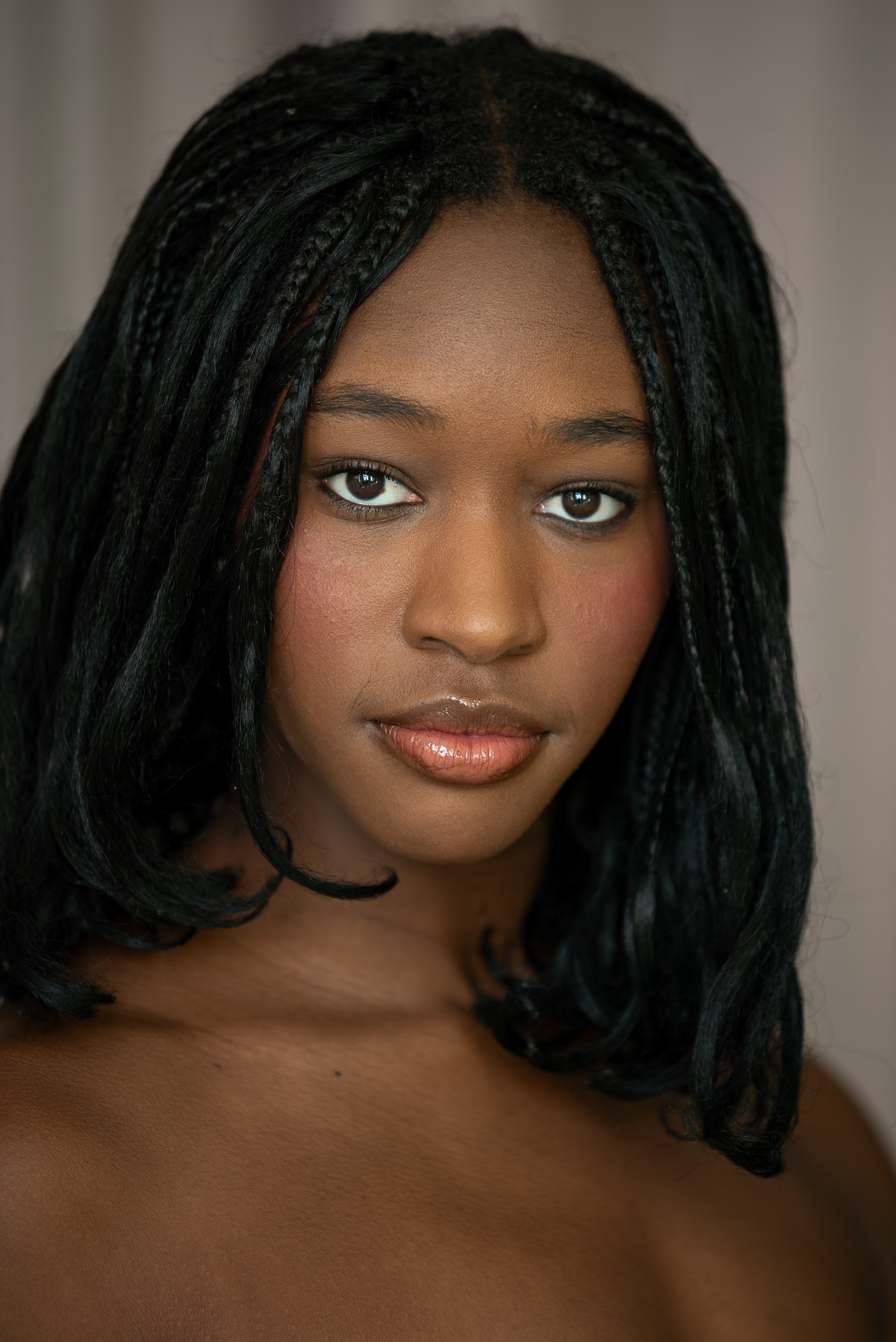 student with brown eyes and brown hair in braids with a center part. 
