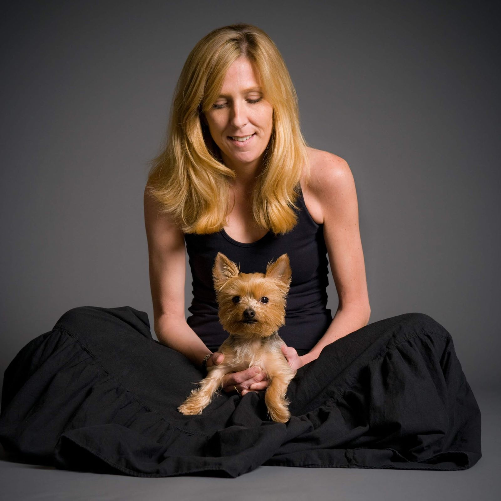 Maura Mandt dressed in a black dress with a small dog on her lap