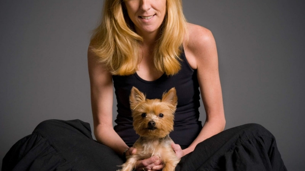 Maura Mandt dressed in a black dress with a small dog on her lap