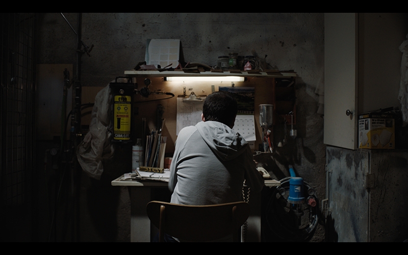 An image of the back of a young man sitting at a workstation.