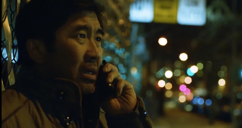 A man on a cellphone standing in a dark street.