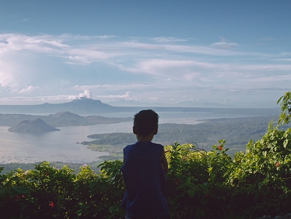 Film Still from Supot. Image of boy looking out over mountains into beautiful bay.