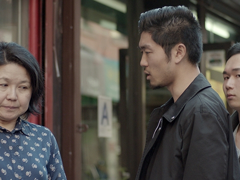 Film Still from Un vase à Chinatown. Image of middle aged Chinese woman being confronted by younger Chinese man. 
