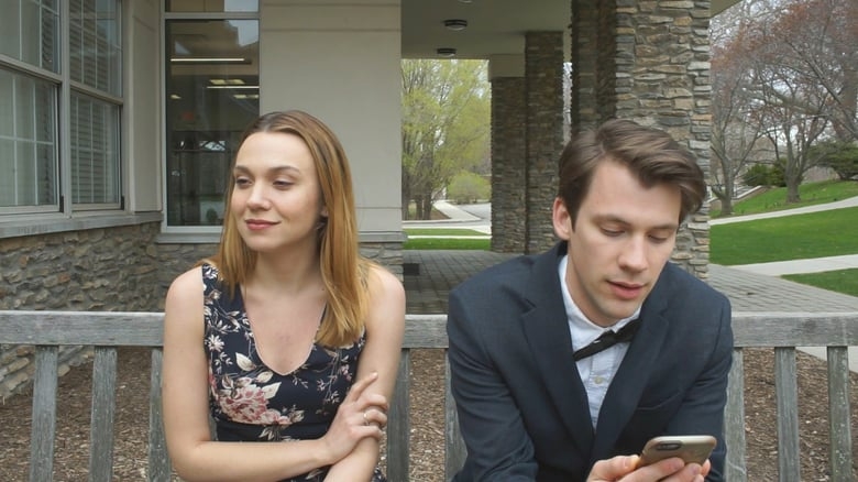 Film Still from Reunion. Woman and man sitting on a bench. Man is looking at his phone.