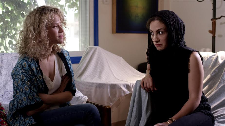 Film still from, "My Dearest Enemy." Two women sitting on couches facing each other. 