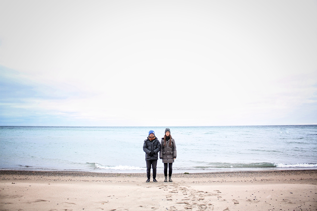 Two people standing along the shore