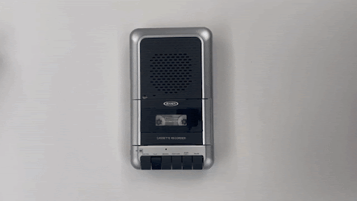 Animated gif of a tape recorder with tapes, a manila folder, and a notebook being placed next to it