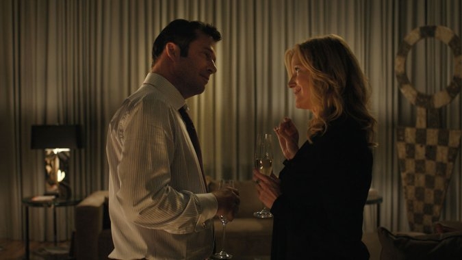 An image of a man and a woman having a drink in a hotel room.