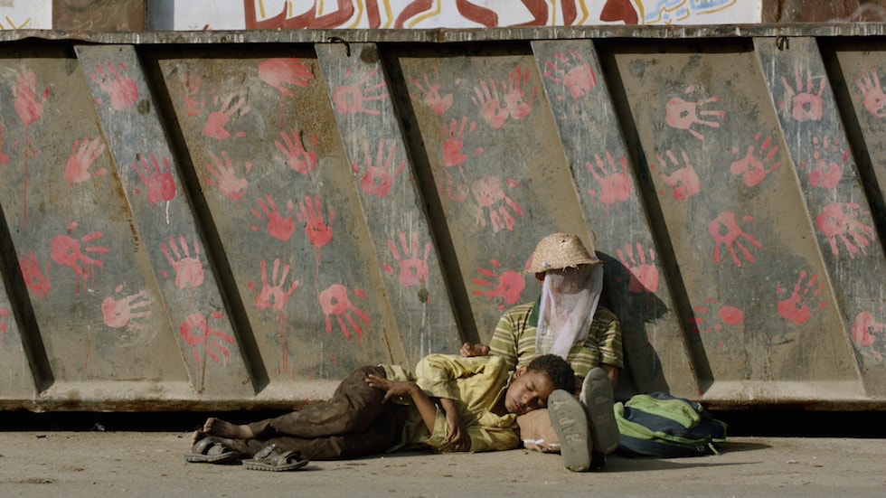 Still from Yomeddine, two young men sleeping on the street in the hot sun.