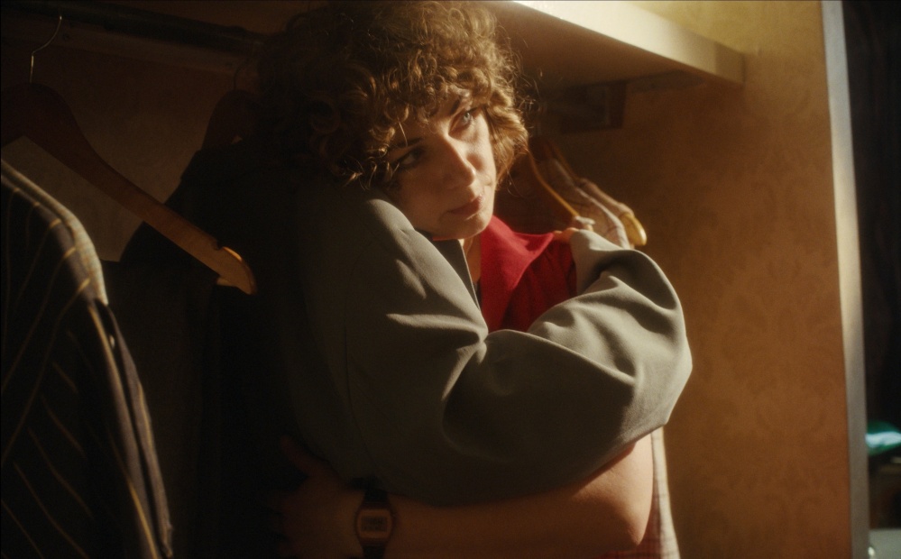 Still from Habitat Hotel. Person in closet holds jacket.