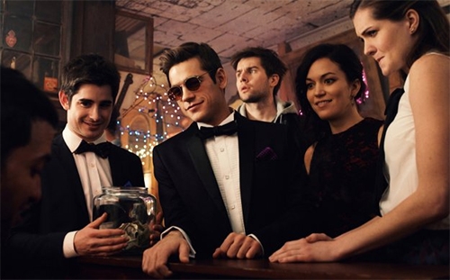 A group of young people in tuxedos and gowns at a party.