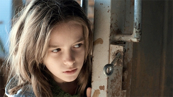 An image of a young child looking from behind a door.