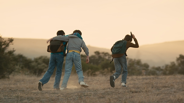 Film Still from Yosemite, image of 3 boys running through the desert. 