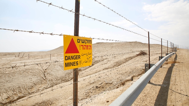 image of a sign on barbed wire in the desert that says DANGER MINES!