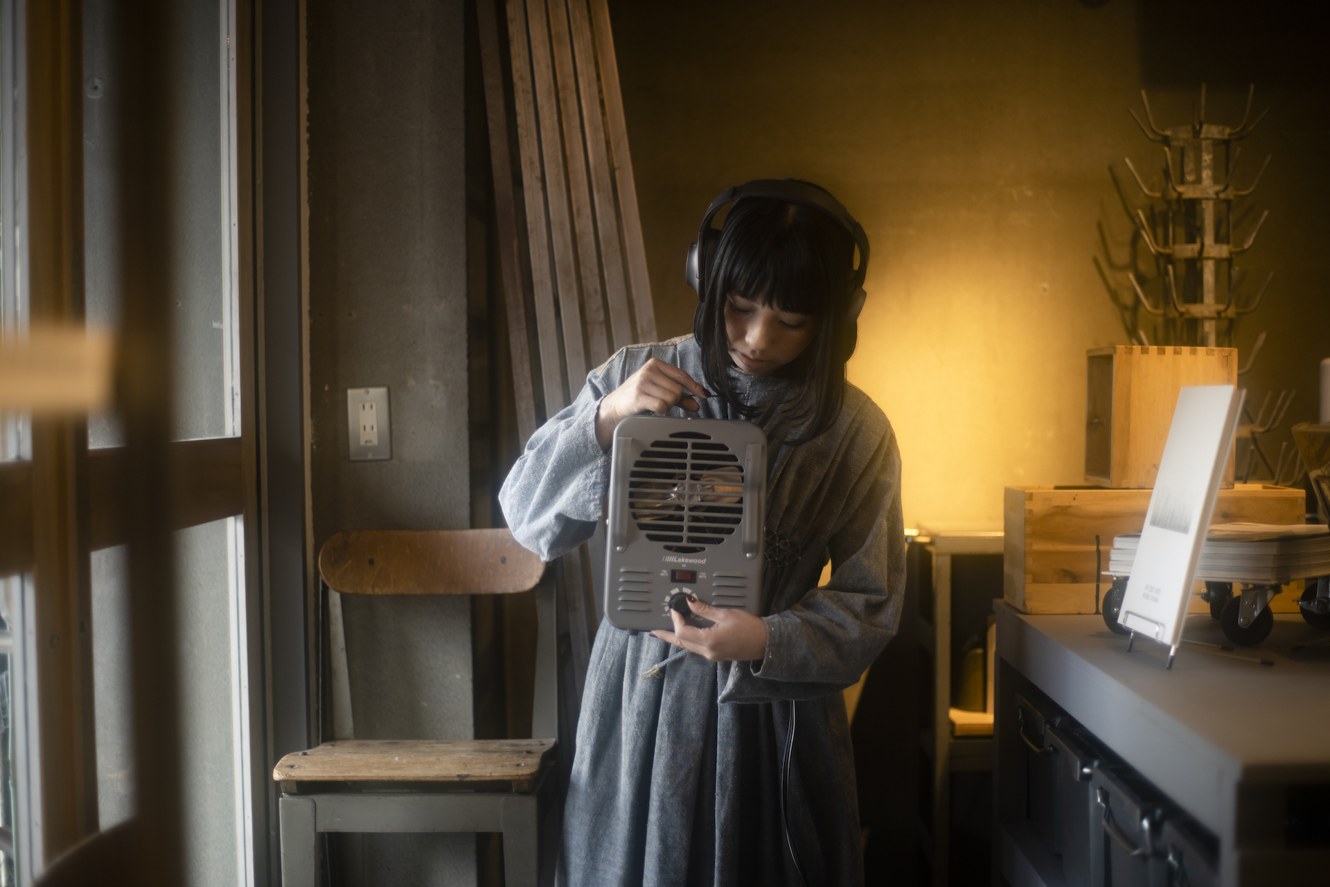 Sawako in a room wearing headphones and holding a device.