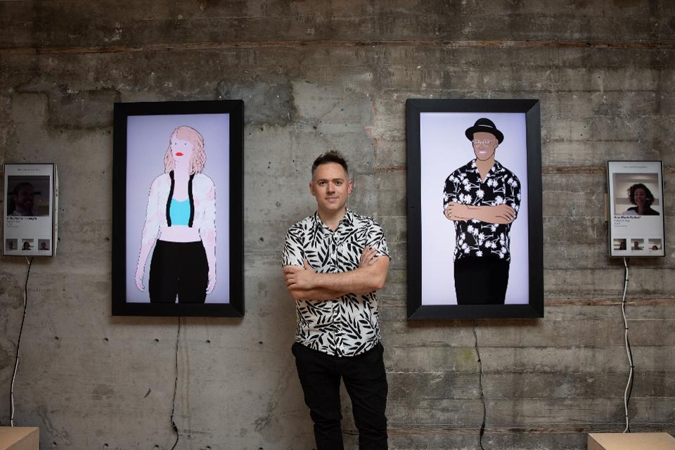 Gabe stands beside two human-sized screens depicting artistic images of people