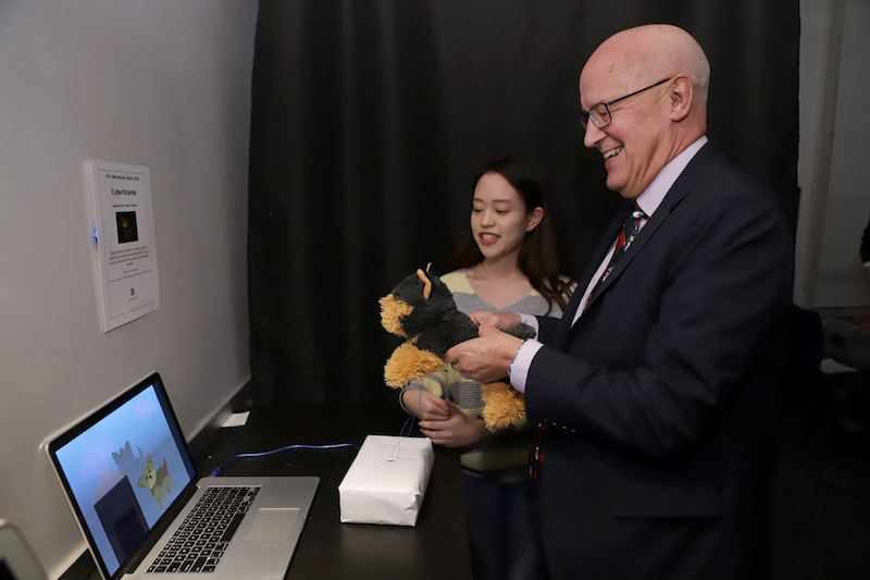 Andrew Hamilton holds stuffed animal while using student project