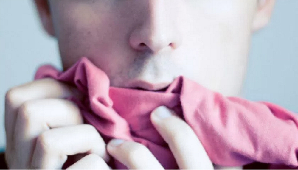 a closeup of a man sniffing a pink shirt