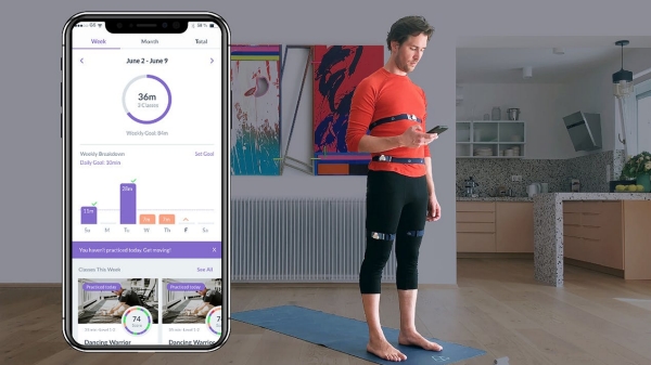 Man wears yoganotch on his torso and legs and looks down at his readings on his phone