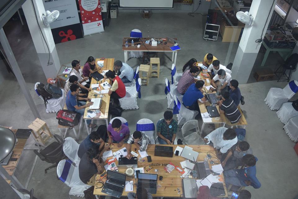 An aerial shot of many people gathered around laptops working.