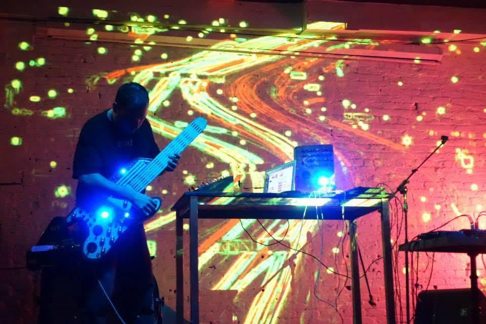 a person playing an electric guitar with a lot of swirly patterns projected on the wall